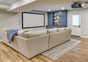 basement renovation with projector and screen and custom cabinetry